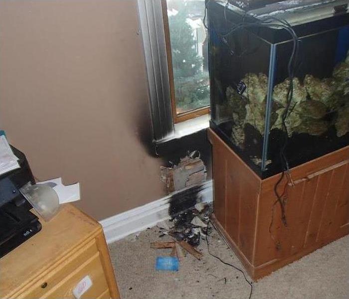 fire damaged wall and window casing behind a fish tank